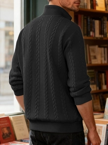 Detail shot of men's black cable knit sweater with a high neck half-zip in a bookstore