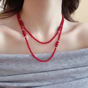 Detail of red beaded double-layer necklace with gold spacers on a model's neck