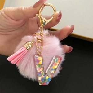 Detailed shot of pink pompom keychain with clear resin letter V and heart glitter
