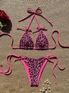 Detailed flat lay of pink leopard print bikini with neck ties and pearl accents