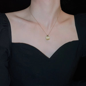Modèle portant un collier en acier titane doré avec pendentif carré en pierre œil de chat