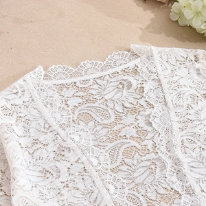 Close-up of white floral lace neckline with scalloped edges and intricate embroidery