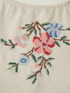 Détail de la broderie florale vintage sur le tissu en coton et lin beige