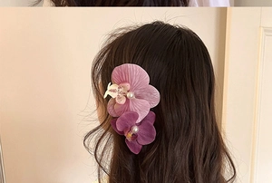 Detailed close-up of lifelike orchid hair clips with elegant pearls worn by a model