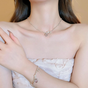 Elegant silver-tone heart and bow necklace and bracelet set worn by a female model