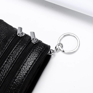 Macro detail of black pebble leather coin purse with three zippers and silver keychain