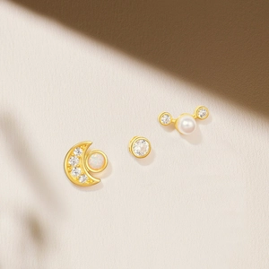 Detail of 925 silver earring set with pearl, opal and crescent moon in gold finish