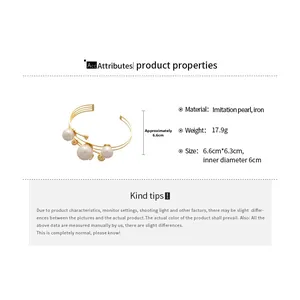 Detail view of gold iron layered open cuff bracelet with white imitation pearls