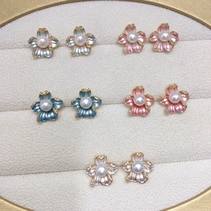 Five pairs of floral pearl earrings in assorted colors on a beige velvet jewelry tray