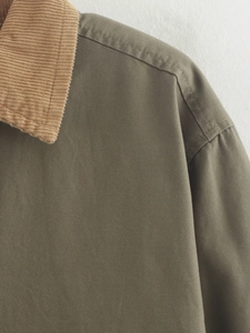 Detail of military green canvas jacket featuring brown corduroy collar and fine stitching