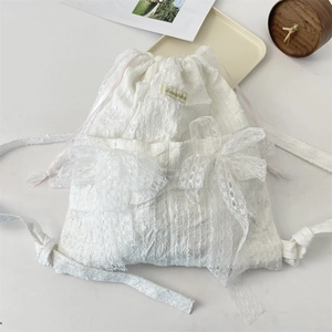 Detailed macro of white lace drawstring bag with delicate bows and floral textures