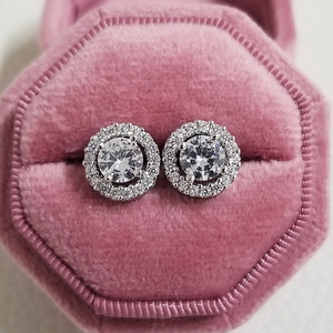 Close-up of halo stud earrings with round zircons in a pink velvet jewelry box
