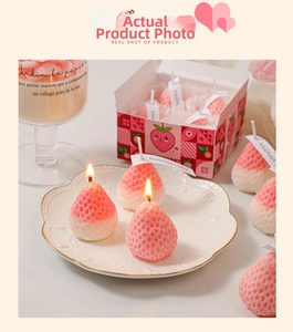 Detail of strawberry-shaped soy wax candles with realistic texture in a pink gift box