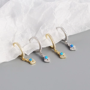 Dettaglio ravvicinato di orecchini a cuore con opale blu in finiture oro e argento