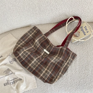 Detail of vintage brown plaid tote bag on a soft white faux fur background