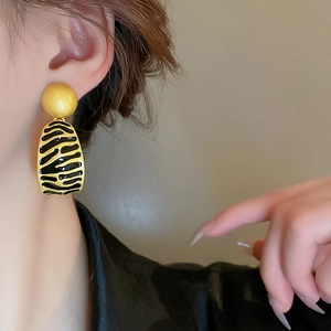 Vintage irregular geometric gold earrings with black enamel stripes worn by model