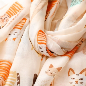 Close-up of lightweight fabric showing detailed cartoon cat patterns on a beige scarf
