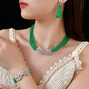 Detail of green beaded jewelry set with silver flower clasps worn by a professional model