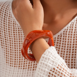 Close-up of orange marble resin cuff bracelet with irregular twisted geometric design