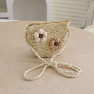 Detail of child's straw crossbody bag featuring crochet flowers and a silver zipper