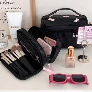 Black cosmetic bag and brush holder set with pink bow detail on a vanity desk