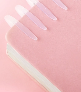 Close-up of four pink translucent glitter bookmarks clipped on a pink leather notebook