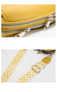 Detail of yellow lychee leather bag with dual silver zippers and woven shoulder strap