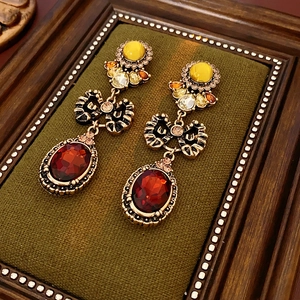 Macro shot of vintage gold earrings with red oval gemstones and crystal bow details
