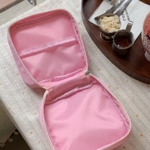 Internal view of pink nylon cosmetic bag featuring mesh organizer and zipper pouch