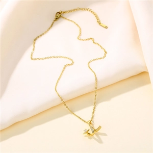 Elegant gold wavy collar necklace with crystal J letter pendant on beige fabric