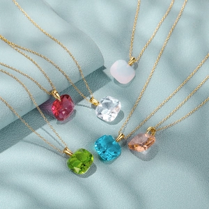 Detail showing six colorful square-cut crystal necklaces with gold chains on blue background