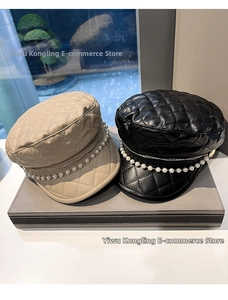 Close-up of quilted leather newsboy hats with elegant pearl and double metal chain decor