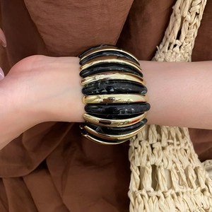 Detail of wide elastic bracelet with gold pieces and black marble acrylic on a model wrist
