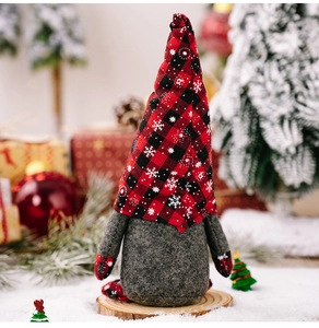 Detailed view of Christmas gnome with red and black plaid snowflake hat on snowy background