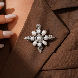 Close-up of vintage cross brooch with pearls and rhinestones on a dark brown suit lapel