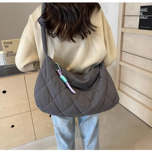 Detailed view of dark grey quilted nylon tote bag with a soft colorful rubber pendant