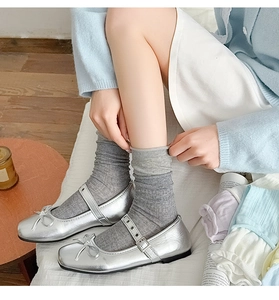Close-up of silver Mary Jane shoes with grey knit crew socks and a small bow detail