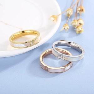 Three-color stainless steel shell rings with zircon accents on a blue background
