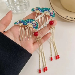 Detailed close-up of golden Chinese fan hair comb with blue enamel and tassel accents