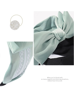 Close-up of mint green and black bow headband with delicate lace embroidery detail