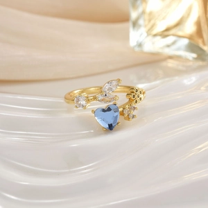 Macro shot of gold ring with heart-shaped blue gemstone and marquise zircon accents