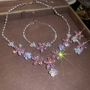 Detailed close-up of zircon flower jewelry set featuring pink and clear stones on a brown tray