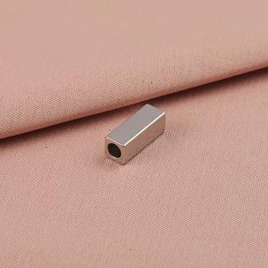 Perle rectangulaire en acier inoxydable poli avec trou central sur tissu rose