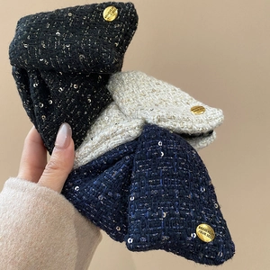 Detail of tweed bow hair clips with sequins and engraved gold metal buttons