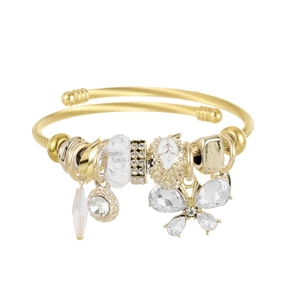 Detailed macro of gold spiral bangle featuring crystal butterfly and pave bead charms