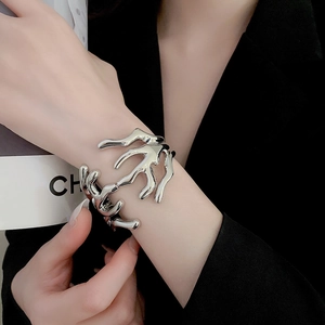 Close-up of silver fluid coral-shaped metal cuff bracelet on model in black suit