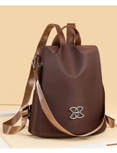 Detailed view of dark brown waterproof nylon backpack with silver infinity logo and wide straps