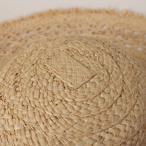 Handmade oversized raffia straw sun hat with frayed edges and wide brim for beach sun protection