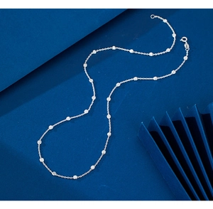 Detailed view of sterling silver necklace with small square bead accents on a blue background