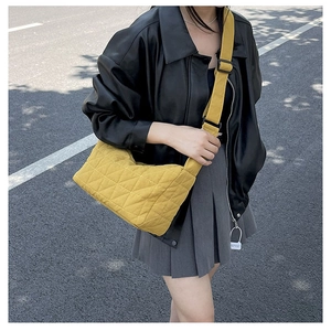 Street style shot of a yellow quilted tote bag showing its size and diamond pattern